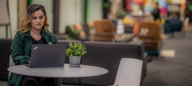 A colleague smiles while using a tablet in a loft-style workspace.