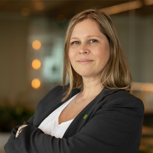 A colleague in a suit folds their arms and smiles in a TD conference room.