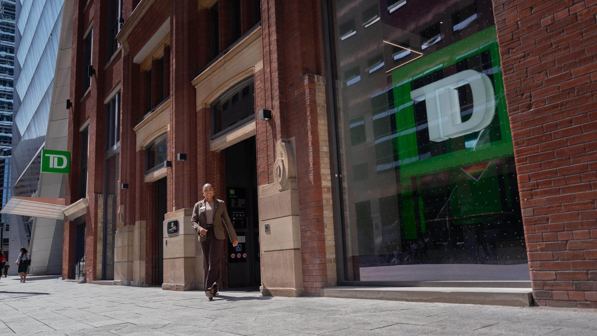 Une femme sourit à l’extérieur d’une succursale de la TD.