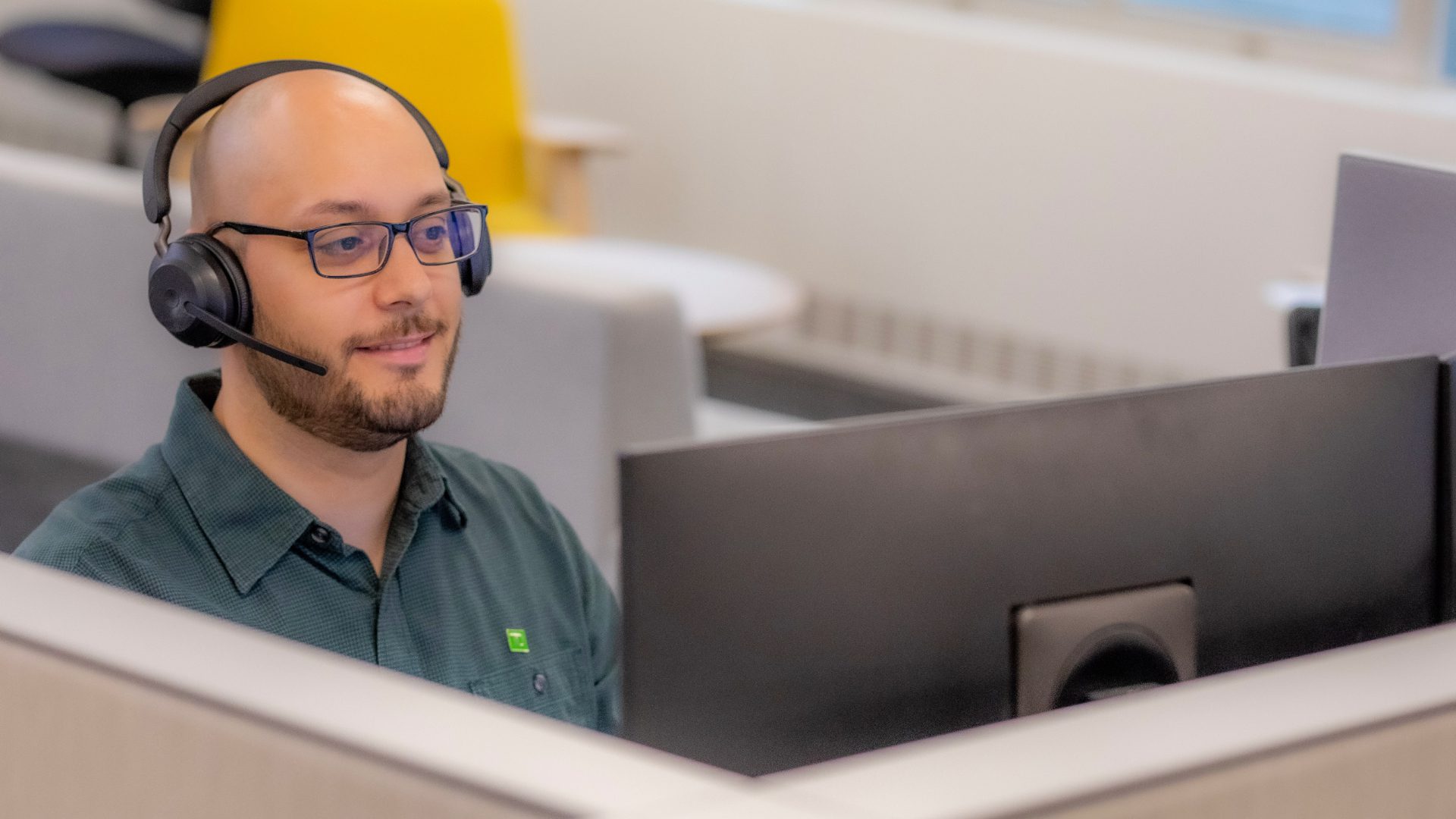 A member of a TD contact centre team wearing a TD green lapel pin and headset looks into the camera.