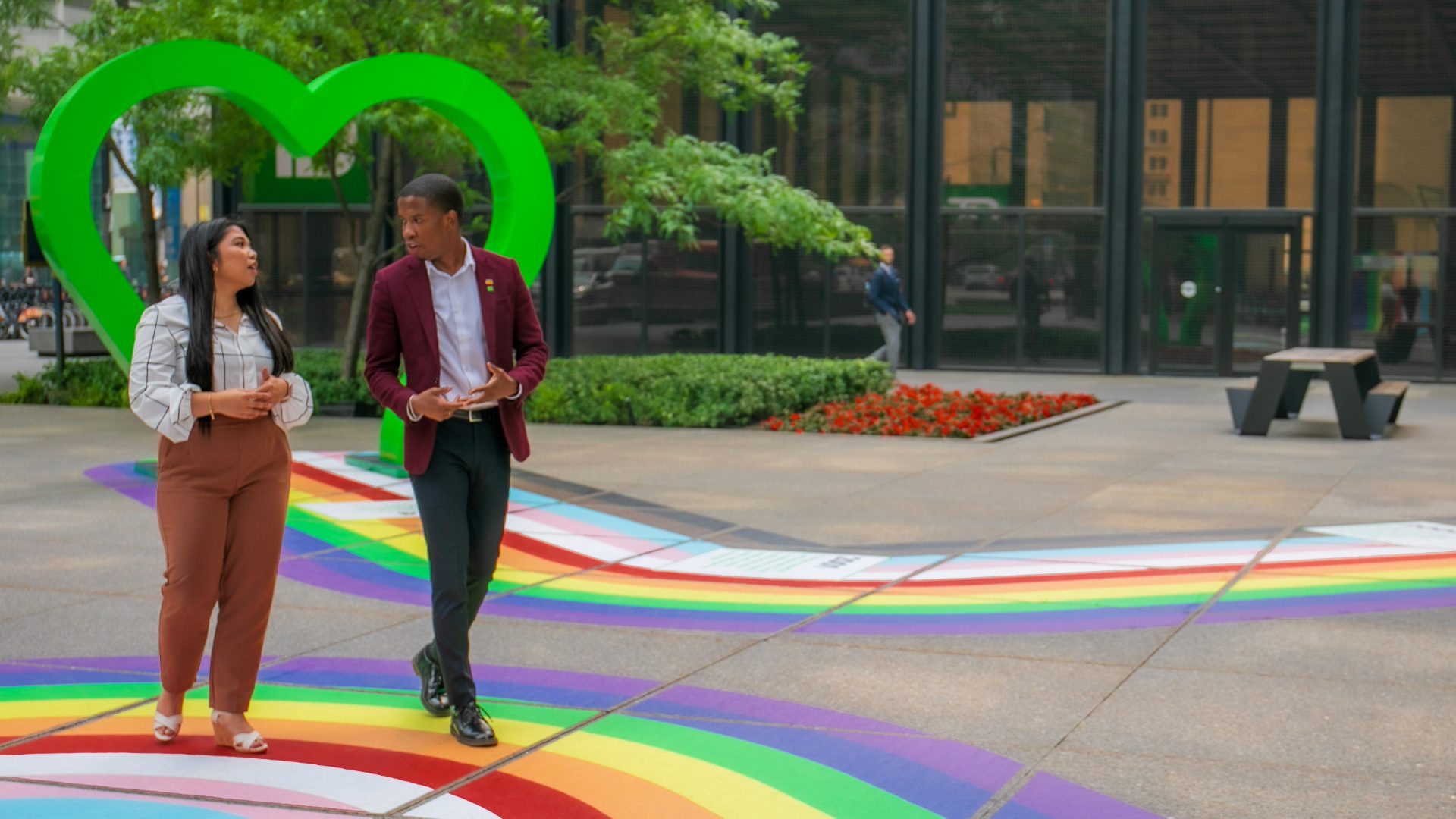 Two colleagues hold a pride flag featuring a Toronto Blue Jays logo.