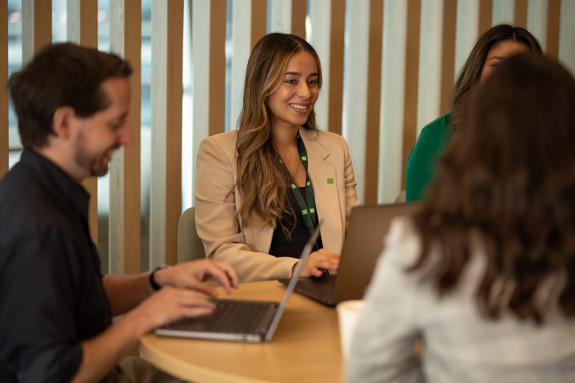 A group of colleagues gather around a boardroom table in an office.