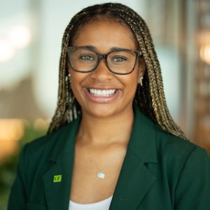 A colleague with a green TD lapel pin smiles at the camera in a TD office.