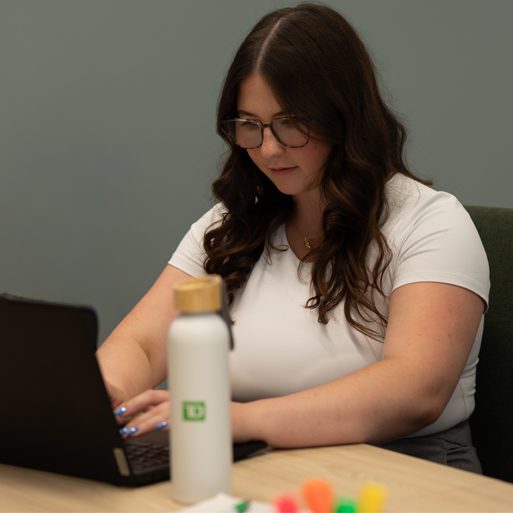 A colleague smiles while presenting some work on their laptop.