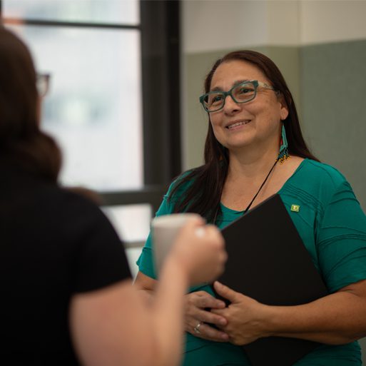 Two colleagues speak together in front of a large window in a TD office.